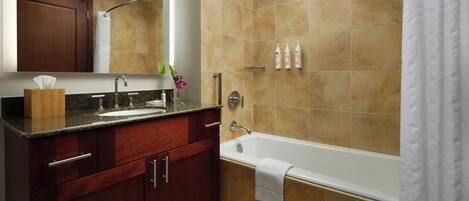 A bathroom with a vanity, sink, mirror, and a bathtub.