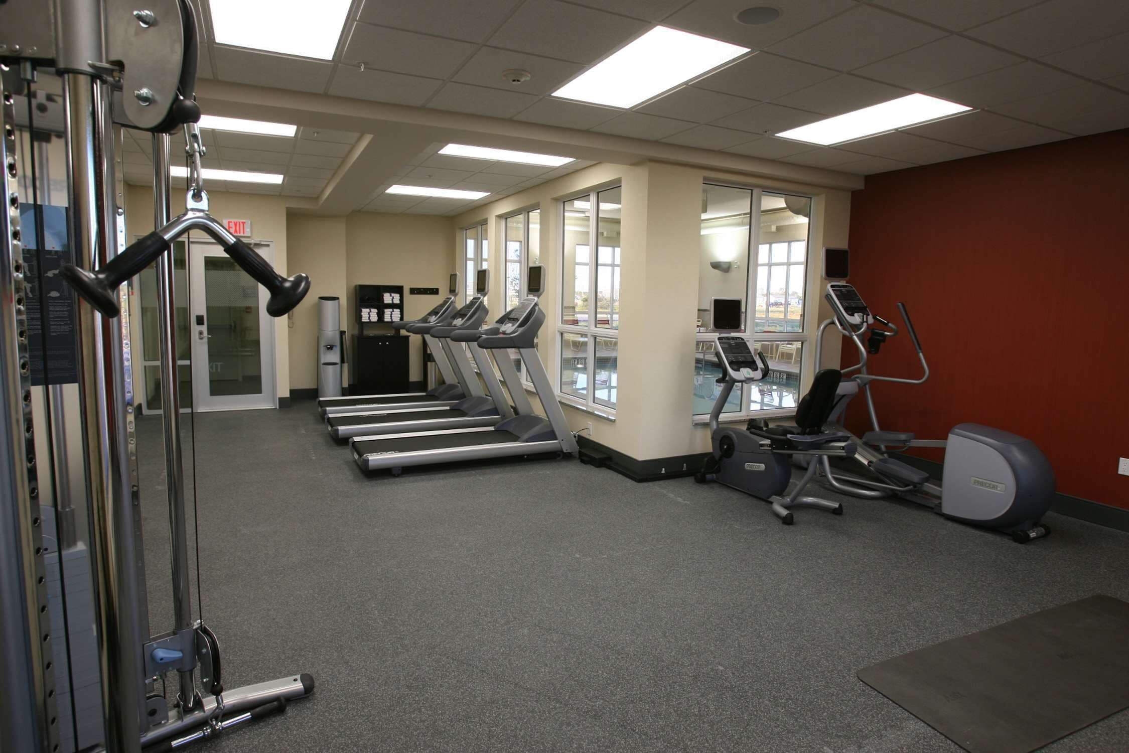 Une salle de sport équipée de tapis de course, de vélos elliptiques et de matériel de musculation.