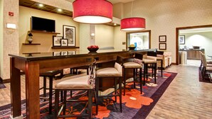 A hotel lobby with a bar area, seating, and a television.