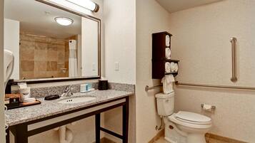 A bathroom with a granite countertop sink, a mirror, a towel rack, and a toilet.