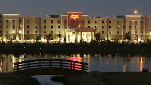 A hotel with a pool, a bridge, and a neon sign.