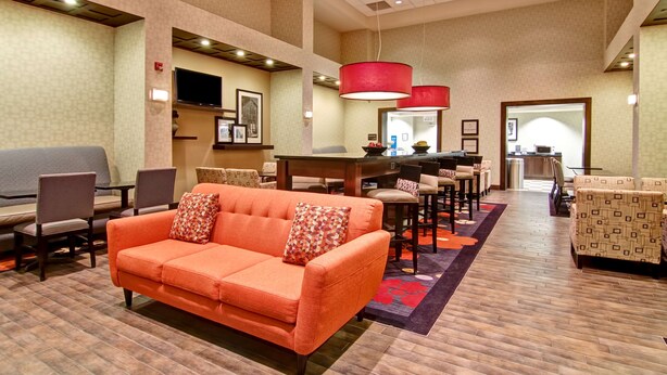 A hotel lobby with a sofa, chairs, a dining area, and a TV.