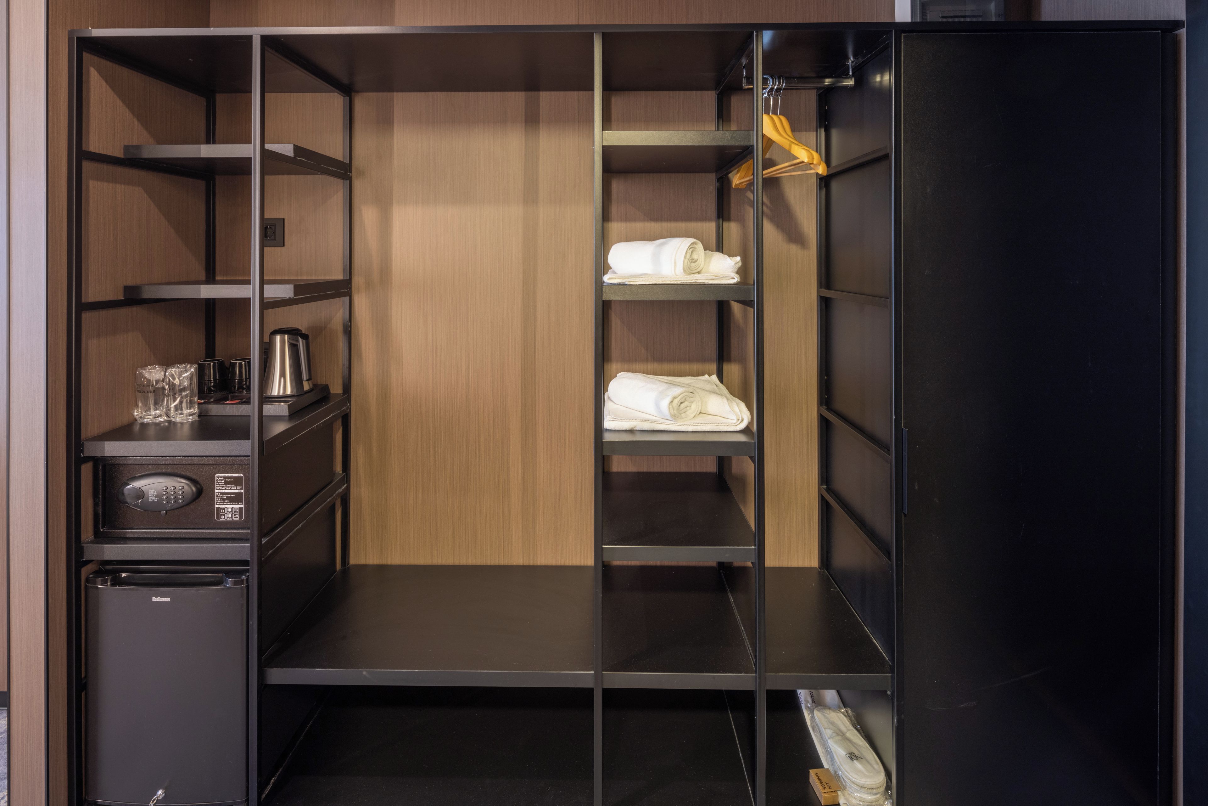 Un vestidor amplio con varias estanterías, un refrigerador compacto y una cafetera.