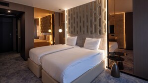 A modern hotel room with a large bed, a bedside table, a mirror, and a wall with a geometric pattern. - Nobel Design (Belgrade)