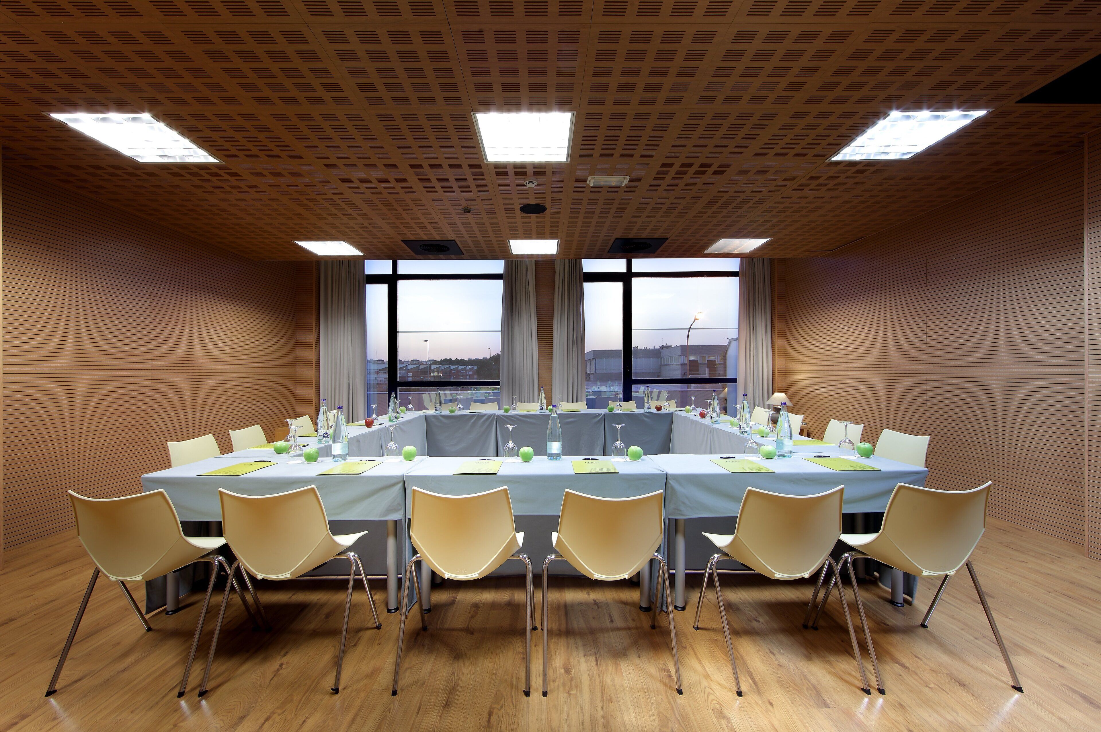 A conference room with a long table, chairs, and large windows with a view.