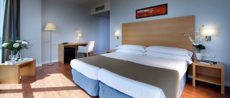 A hotel room with a large bed, bedside tables, a desk, and a chair.
