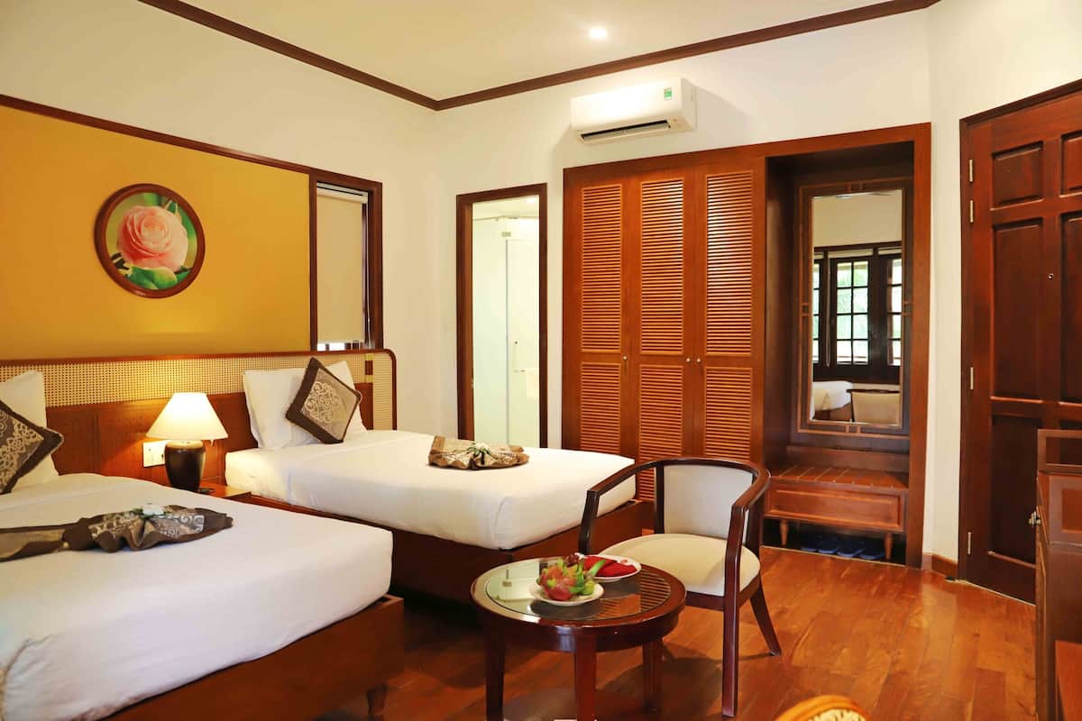 A hotel room with two beds, a sitting area with a table, and a wardrobe.