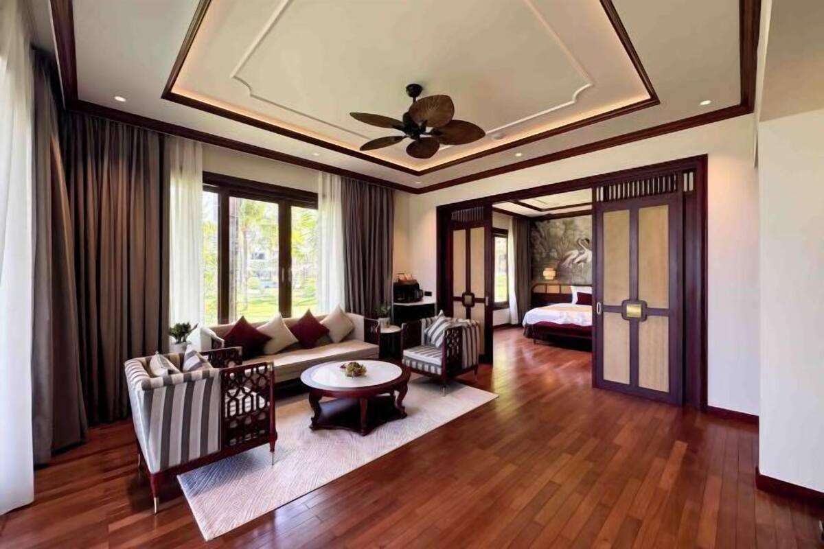 A spacious living room with a sofa, chairs, a coffee table, and a ceiling fan.