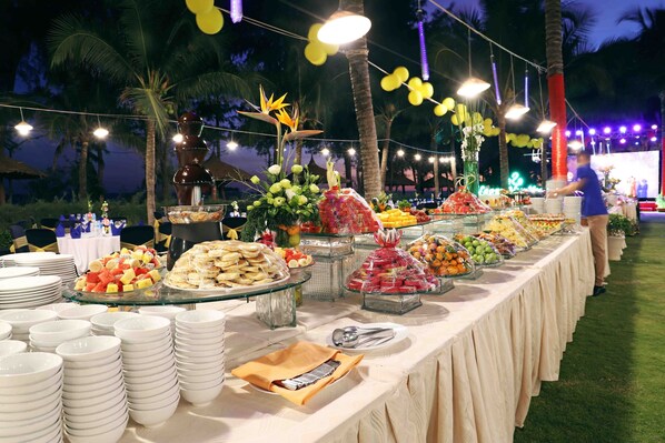 Una mesa de buffet con diversos alimentos y una persona sirviendo.