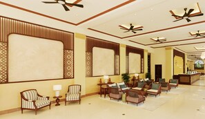 A spacious lobby with multiple seating areas, ceiling fans, and a reception desk.