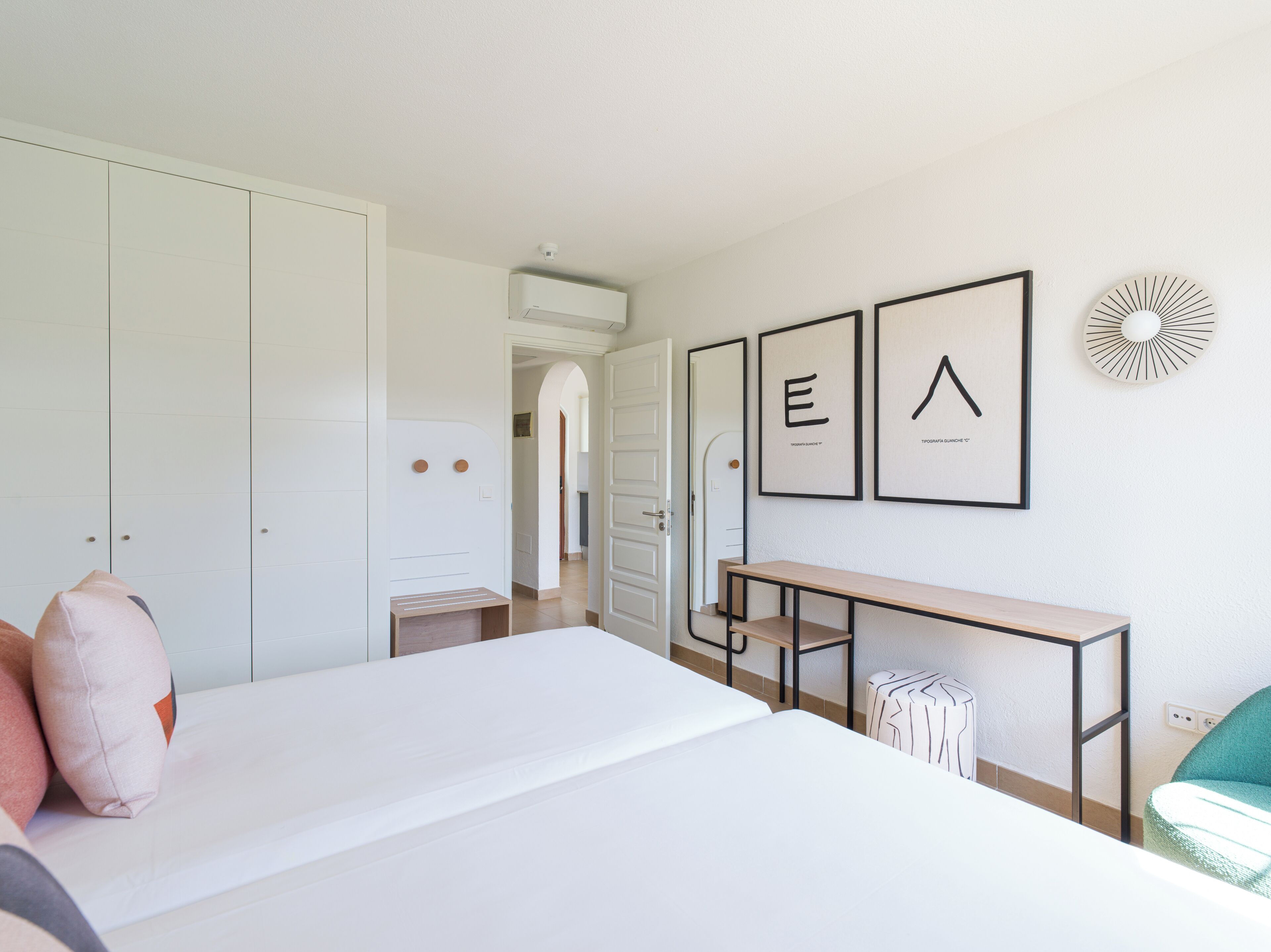 A modern bedroom with a bed, a desk, and a wardrobe.