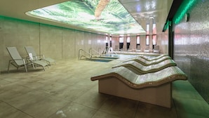 Un espace spa moderne doté d’un grand projecteur au plafond, d’un banc de relaxation et d’une piscine.
