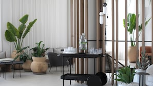 Un salon moderne avec une table basse noire, un canapé et de grandes plantes en pot.