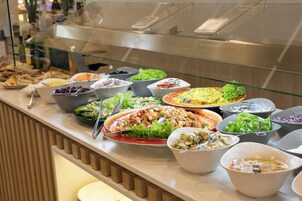 Ein Buffet mit verschiedenen Speisen, darunter Salate, Pasta und weitere Gerichte.