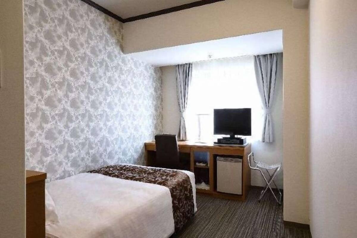 Een hotelkamer met een bed, een bureau met een televisie en een stoel.