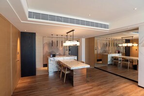 A modern kitchen with a marble countertop, wooden chairs, pendant lighting, and a large mirror reflecting the space. - Sheraton Taoyuan Hotel (Taoyuan City)