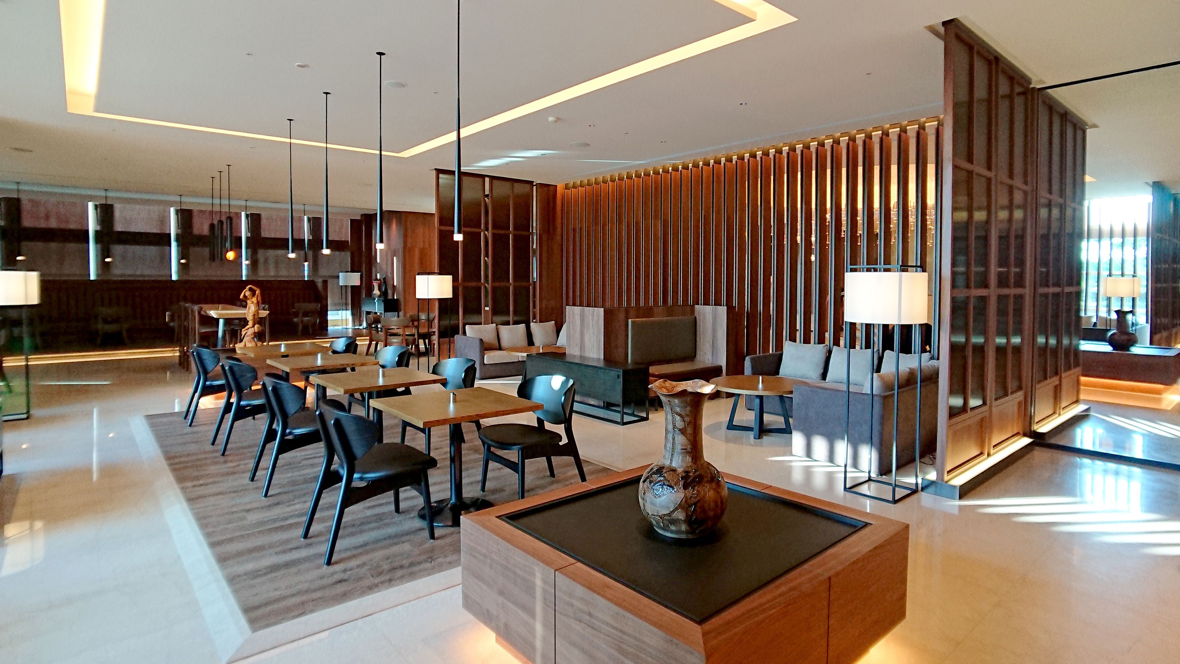 A modern hotel lobby with a seating area, tables, and a decorative vase.
