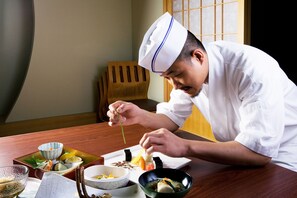 A chef in a white uniform preparing a dish with chopsticks. - Sheraton Taoyuan Hotel (Taoyuan City)