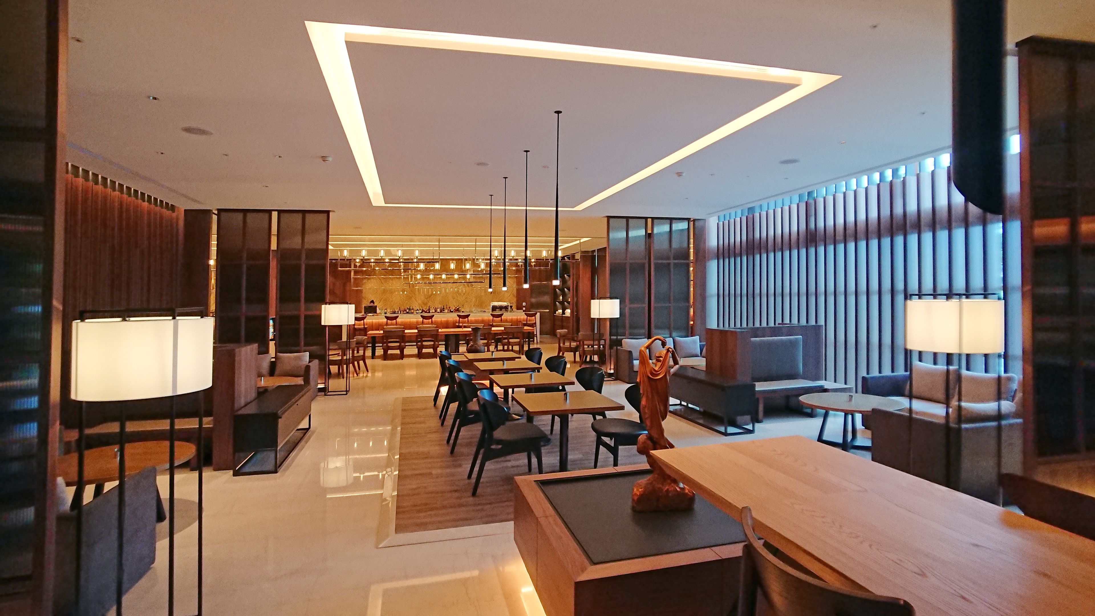 A modern hotel lobby with a bar area, seating arrangements, and a reception desk.