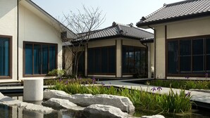 A traditional Japanese-style building with a koi pond, surrounded by rocks and plants.