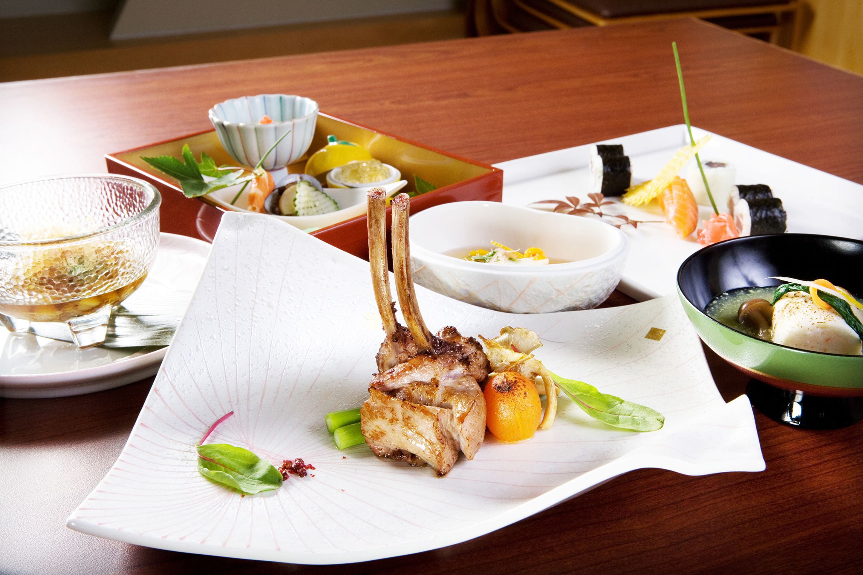 A dining table with various dishes, including a bowl of soup, a plate with meat, and a bowl of vegetables.