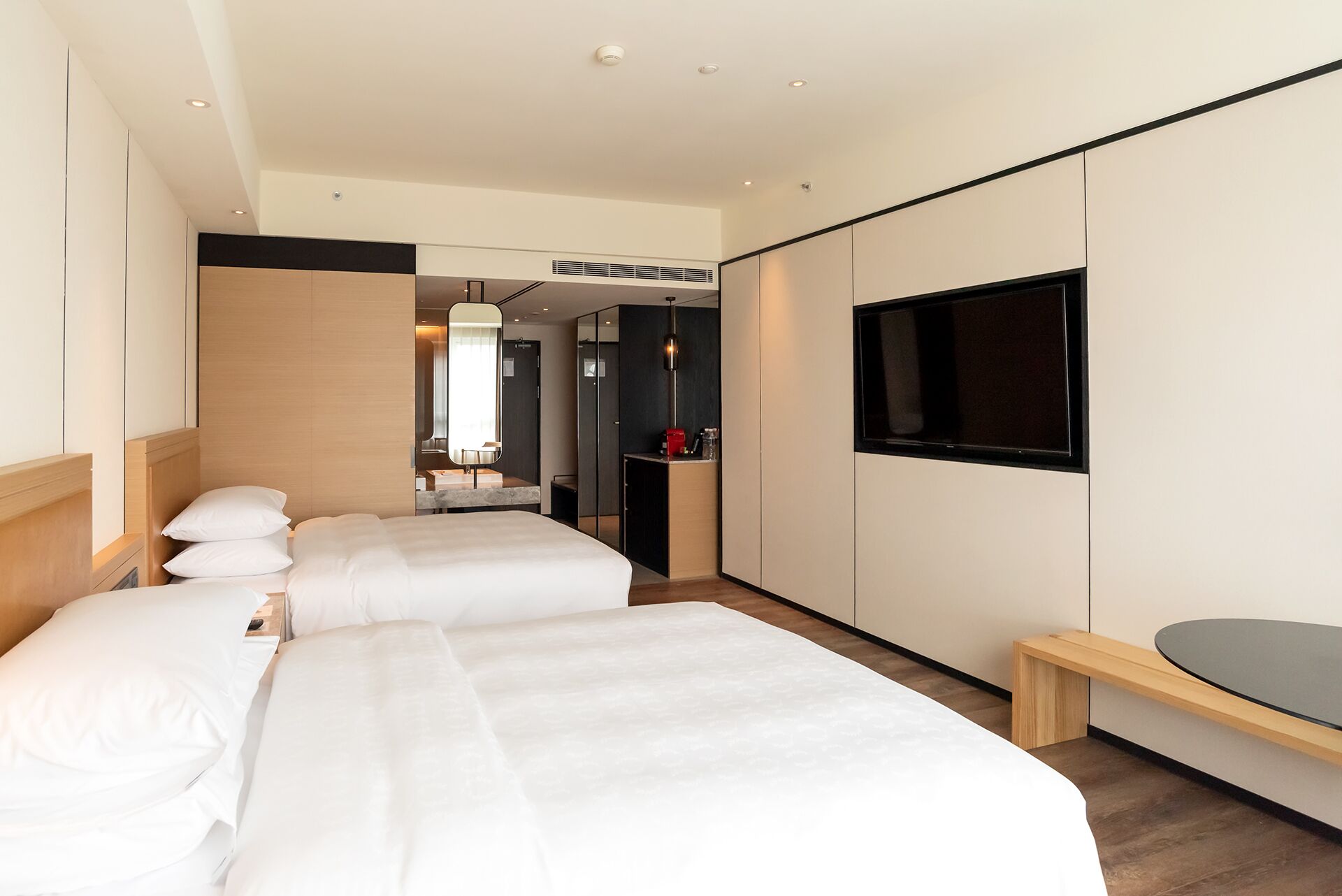 A hotel room with two beds, a TV, and a small desk.