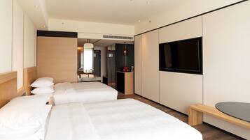 A hotel room with two beds, a TV, and a small desk.