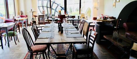 A spacious dining area with a long wooden table set for a meal, surrounded by chairs.