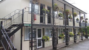 Un edificio de dos pisos con un letrero que dice “The Old Mill Lodge”. Hay escaleras que llevan a la entrada, y el edificio tiene varias ventanas.