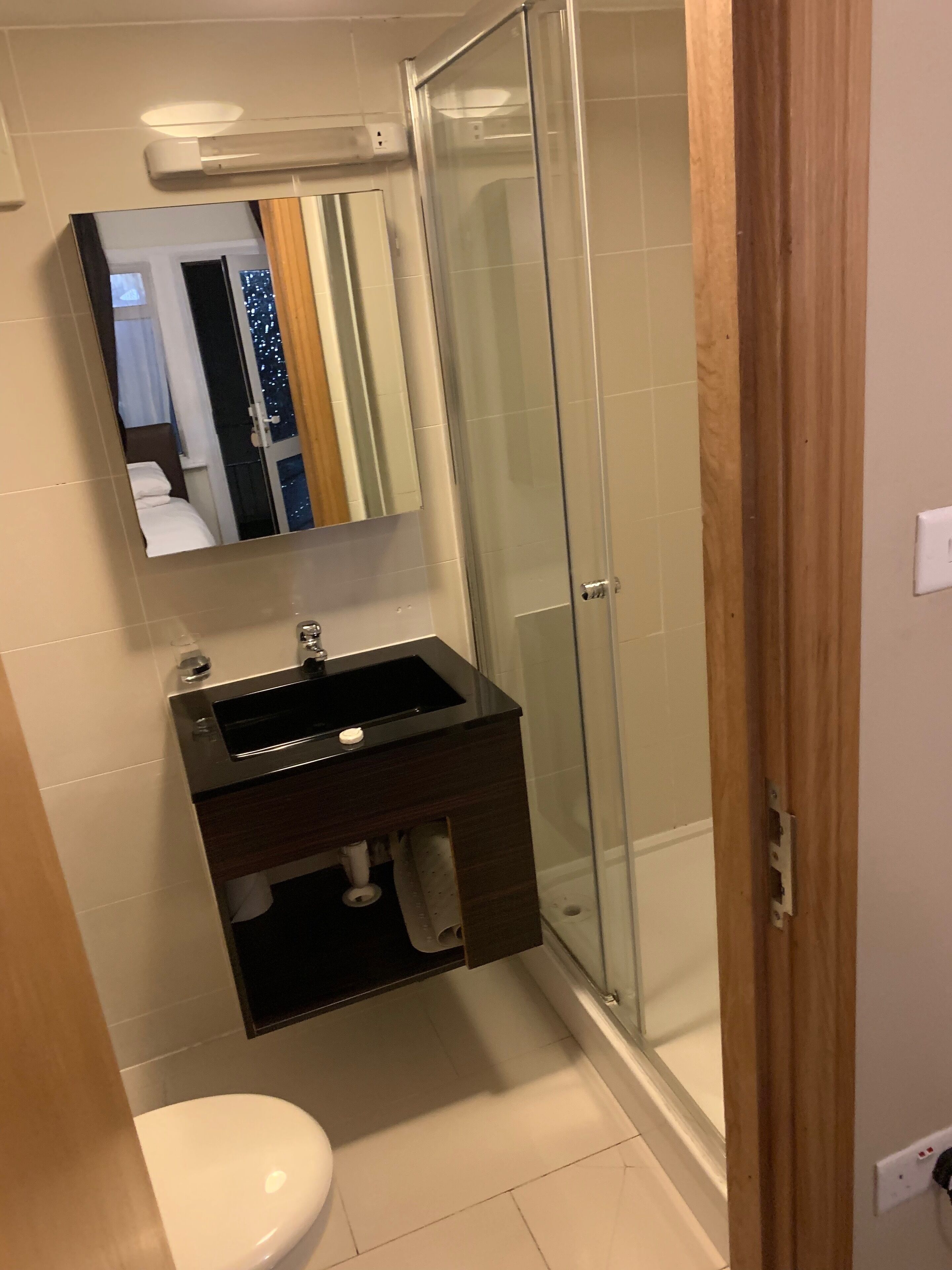 A modern bathroom with a glass shower enclosure, a dark wooden vanity, and a white toilet.