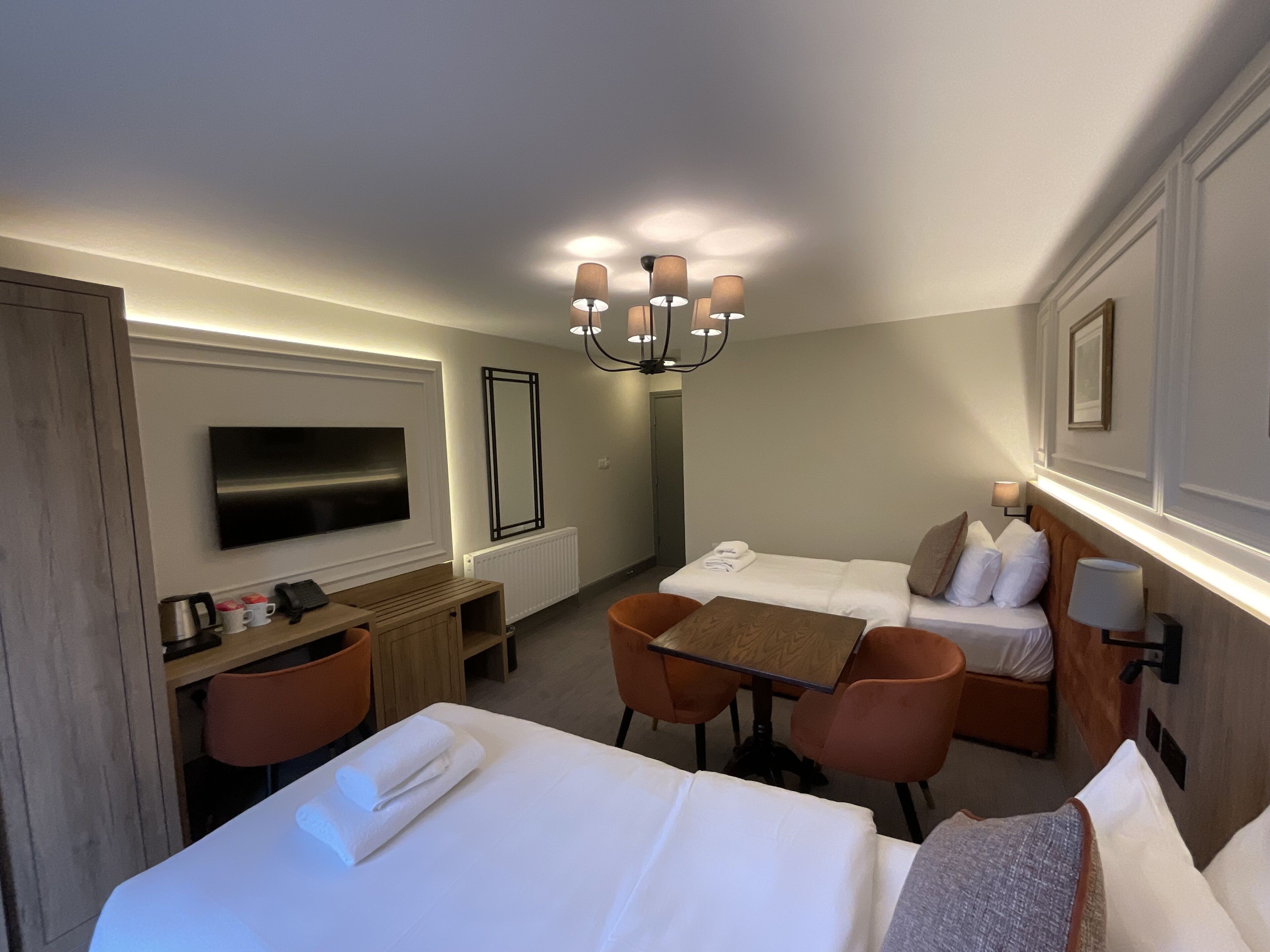 Una habitación de hotel con cama, escritorio, silla, televisor y candelabro.