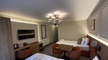 Una habitación de hotel con cama, escritorio, silla, televisor y candelabro.