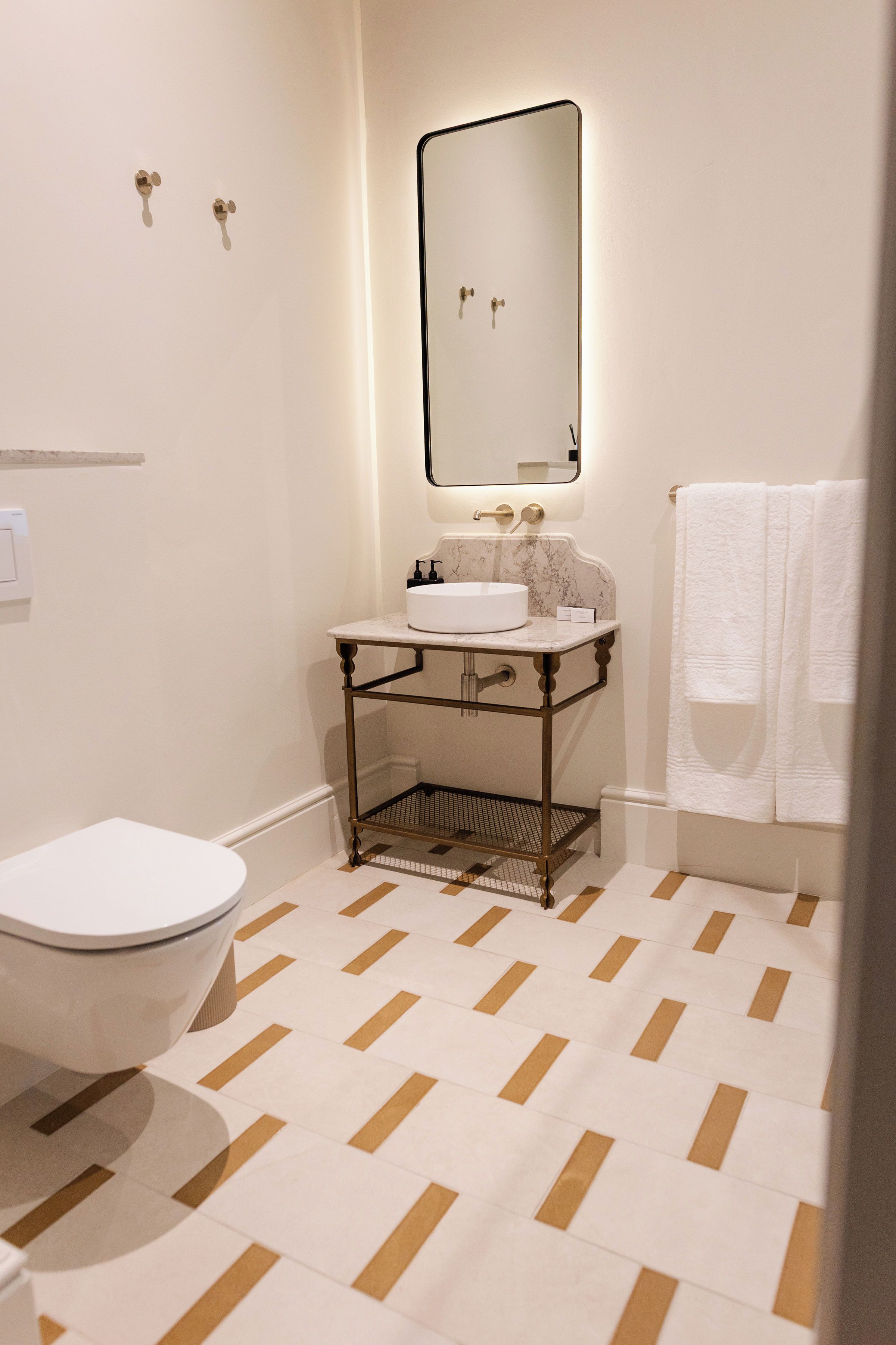 A bathroom with a white toilet, a sink with a marble countertop, a mirror above the sink, and a patterned floor.