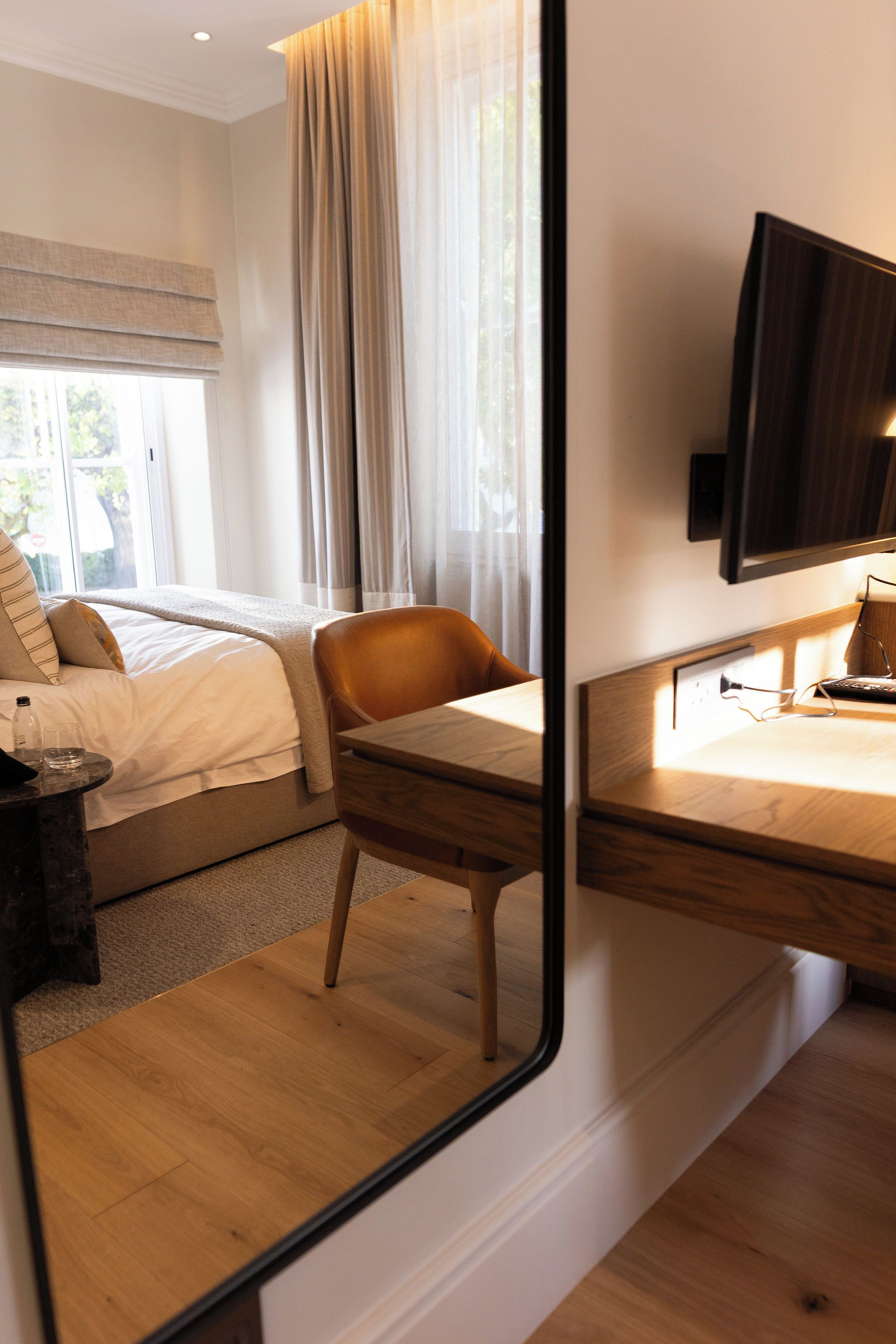 Habitación de hotel con cama, una silla, escritorio y televisión.
