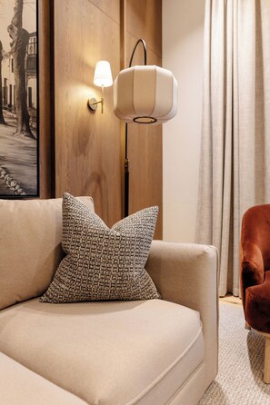 A modern living room with a sofa, a patterned throw pillow, a wall-mounted lamp, and a framed picture. - Eendracht Hotel (Stellenbosch)