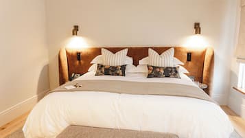 A neatly made bed with a headboard, two bedside lamps, and a bedside table with a glass.