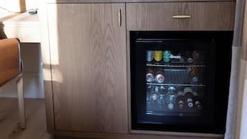 A compact kitchenette with a built-in refrigerator, a coffee maker, and a flat-screen TV mounted on the wall.