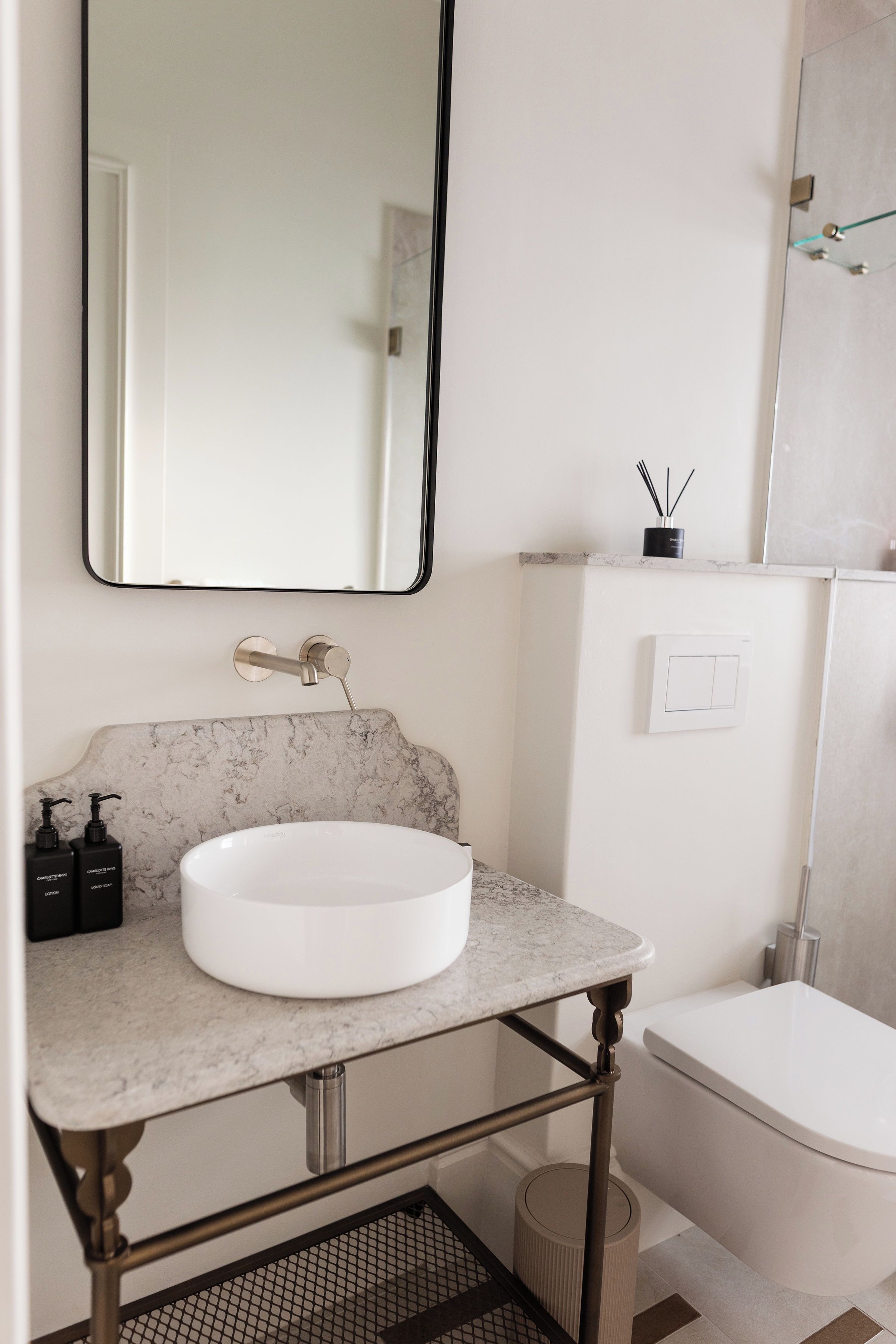 Un baño con lavamanos blanco, un espejo y un inodoro.