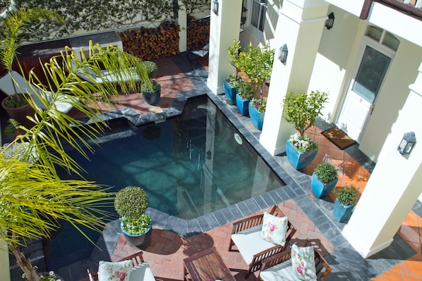 A rooftop pool with surrounding potted plants and outdoor furniture.