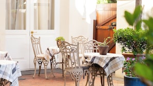 An outdoor patio with a pool, wicker furniture, and potted plants. - Eendracht Hotel (Stellenbosch)
