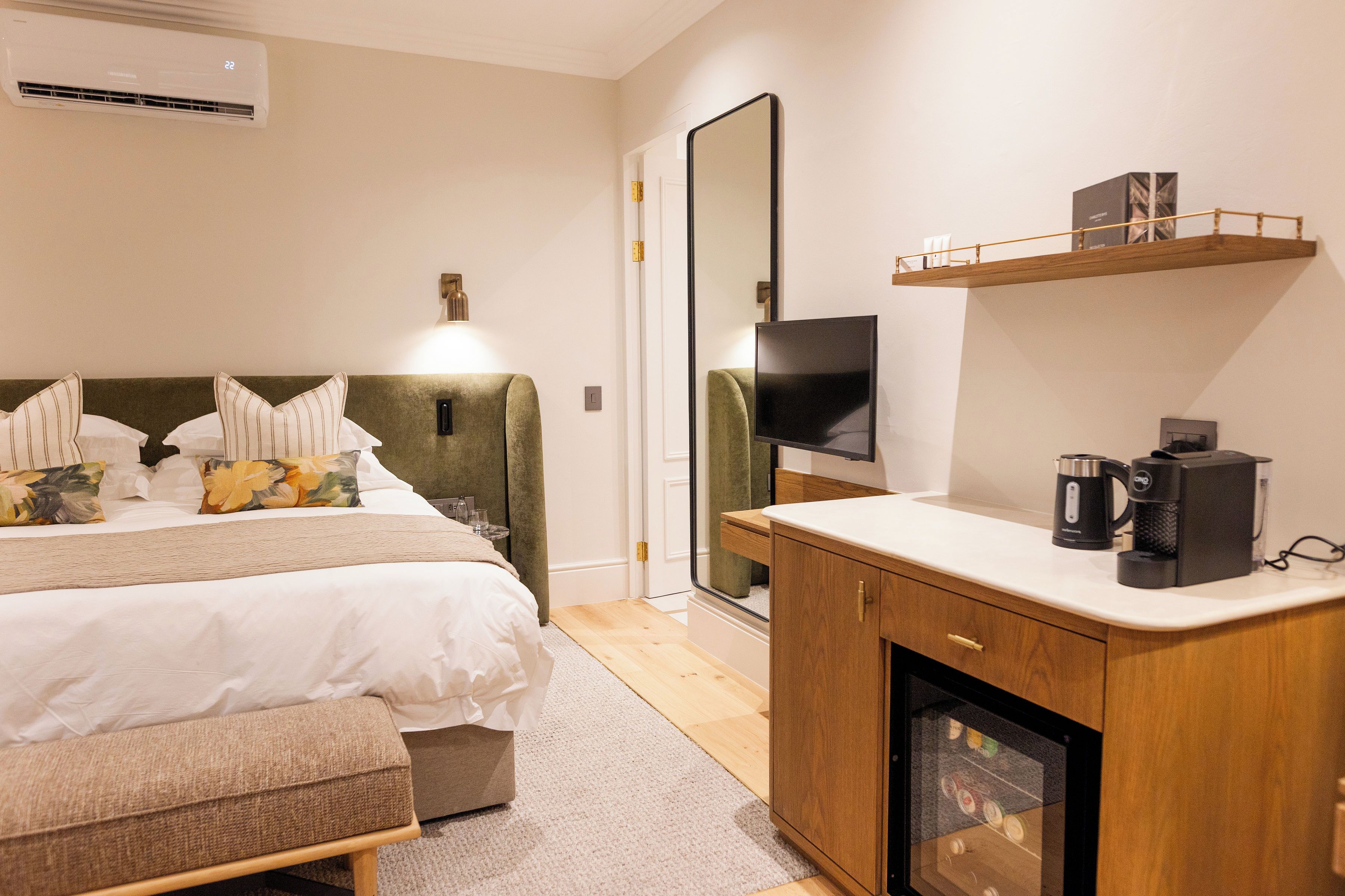 Una habitación de hotel con cama, mesita de noche, televisor y cafetera.