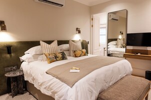 Una habitación de hotel con una cama grande, una mesita de noche, un espejo y un televisor.