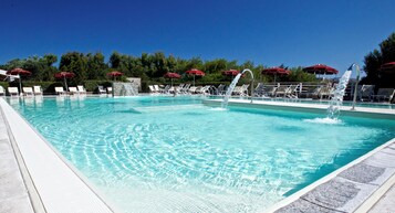 Una piscina al aire libre, sillones reclinables de piscina