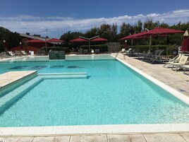 Una piscina al aire libre, sillones reclinables de piscina