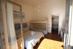 A room with bunk beds, a door with a mirror, and a painting on the wall. - Club Esse Sporting (Stintino)