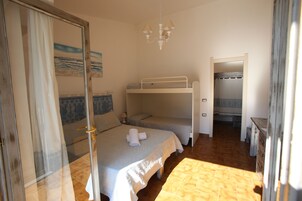 A room with bunk beds, a door with a mirror, and a painting on the wall.