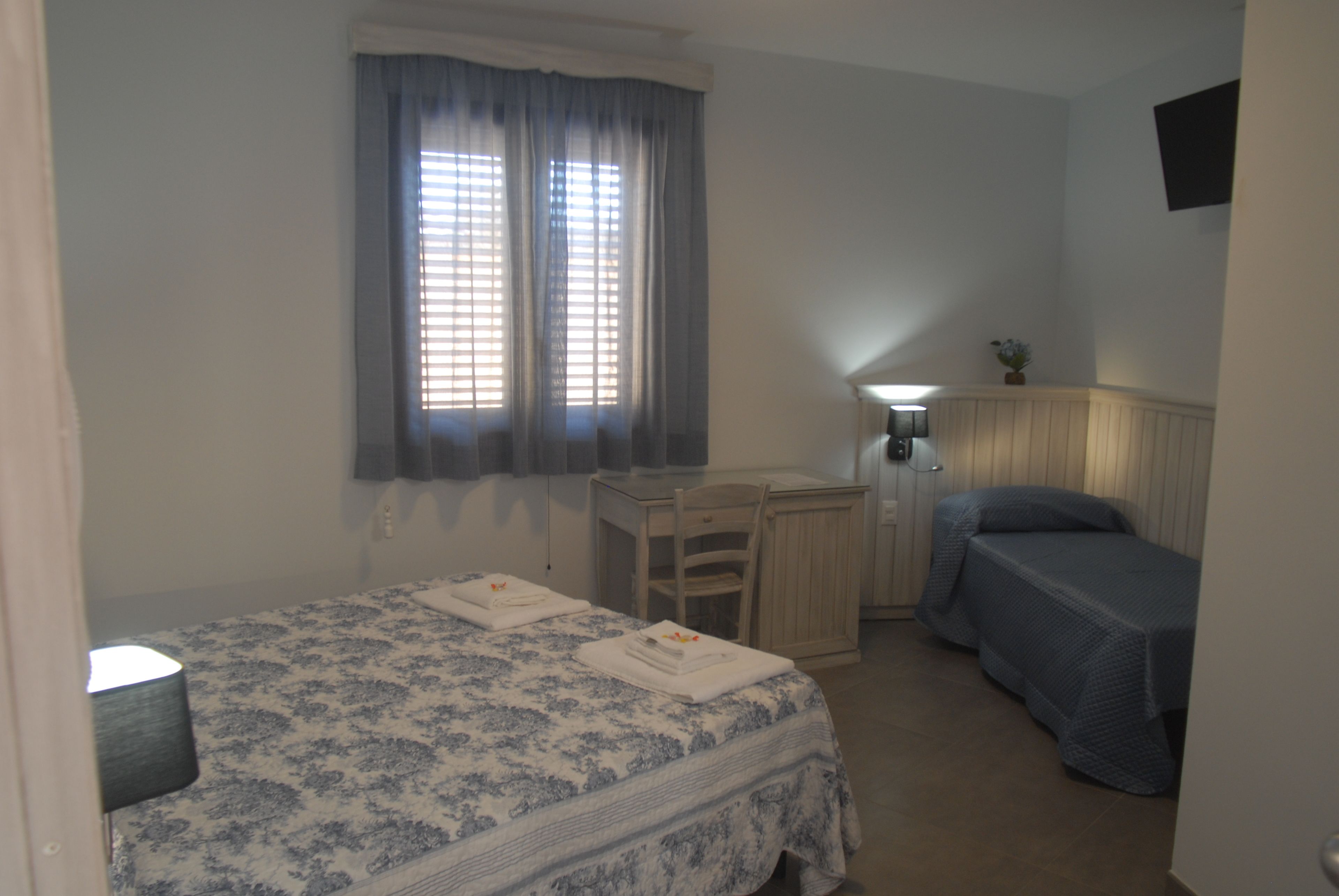 A bedroom with a bed, a desk, and a chair.