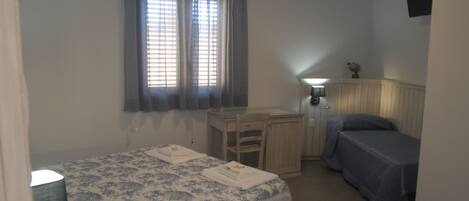 A bedroom with a bed, a desk, and a chair.