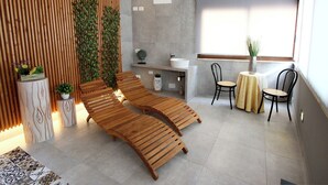 A modern bathroom with a wooden slatted wall, a sink, and two lounge chairs. - Conte Luna (Sciacca)