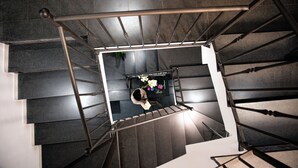 A modern staircase with a metal handrail and a person descending. - Conte Luna (Sciacca)